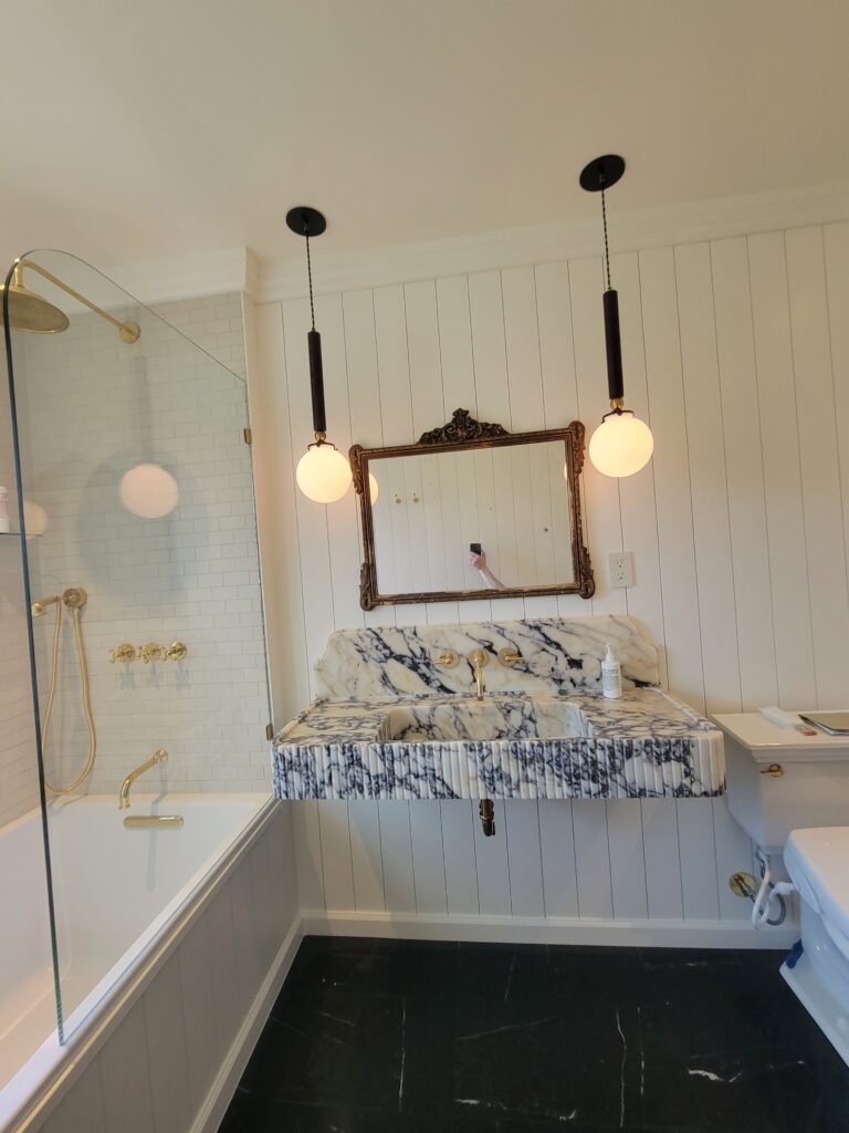 Custom stone vanity beside a glass-enclosed tub and shower