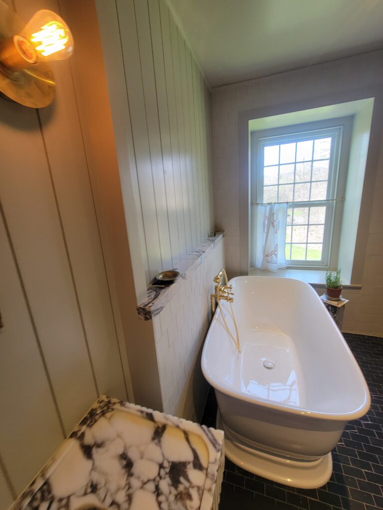 Freestanding tub beneath the window with custom wall finishes