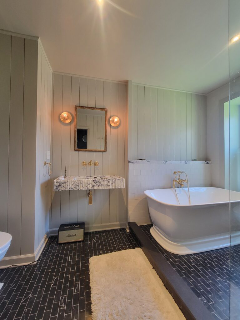 Freestanding tub, wall-mounted sink and dark tile floor