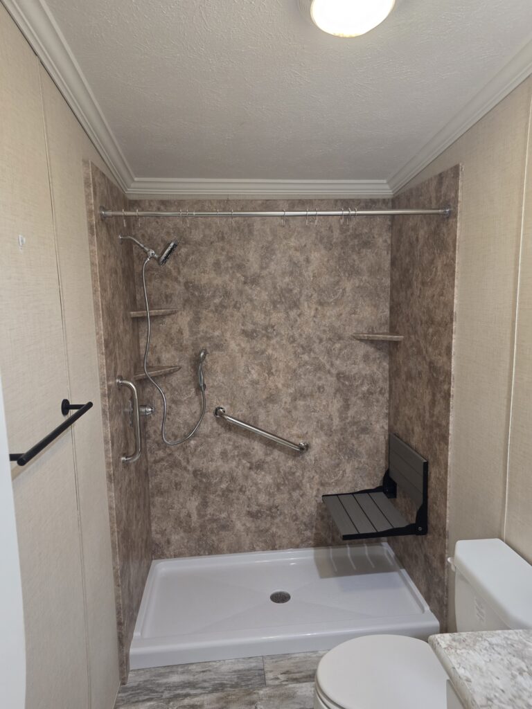 Low-threshold acrylic shower with fold-down seat, grab bars and handheld shower