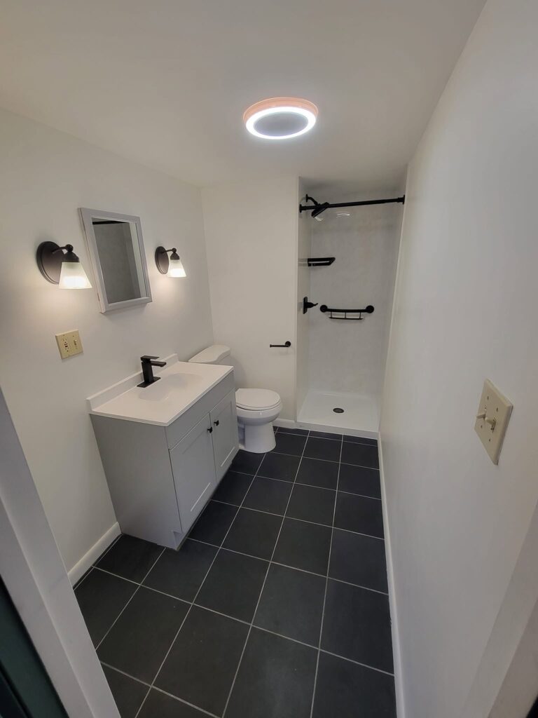 Finished Bethlehem bathroom with gray vanity, white shower walls and black fixtures