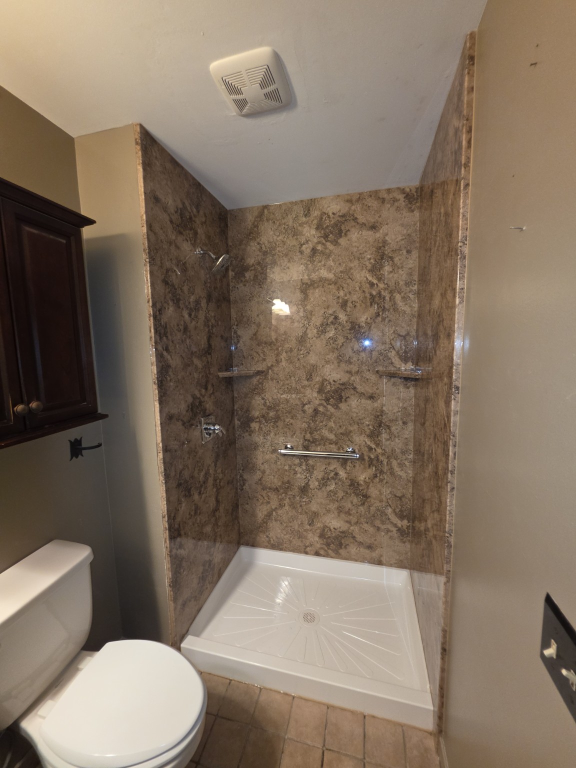 Delmar Madeira Granite-pattern acrylic shower with white base, corner shelves and grab bar, before glass-door installation