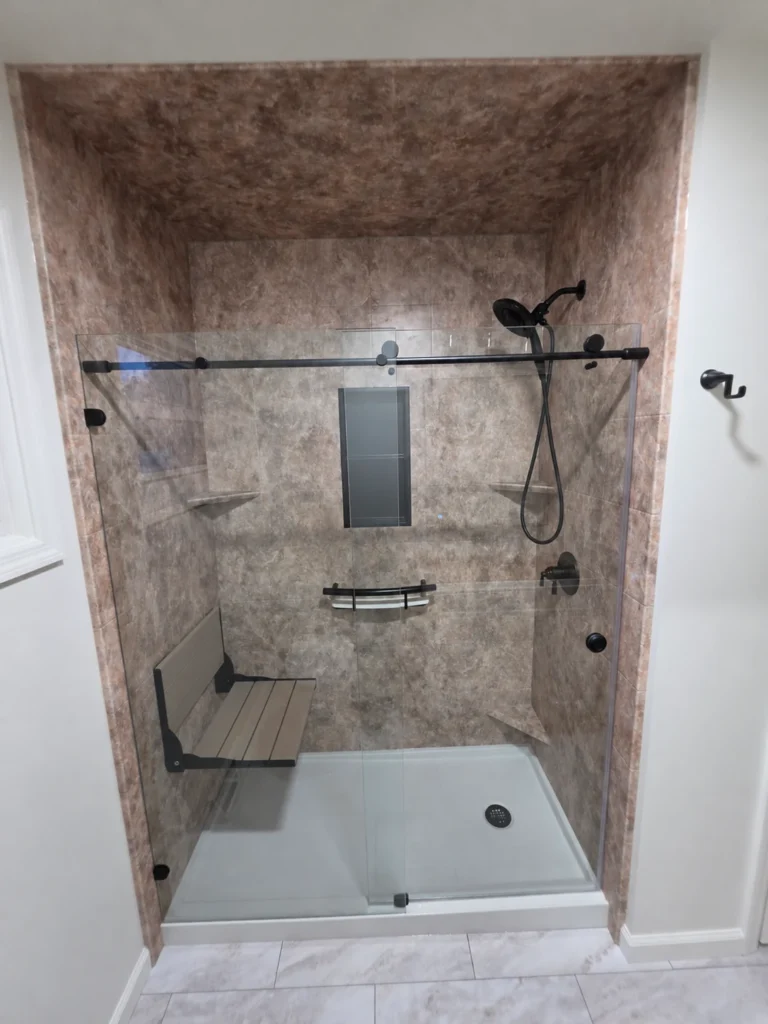 Completed Moore Done Right acrylic shower in Selkirk with glass doors, fold-down seat and handheld shower