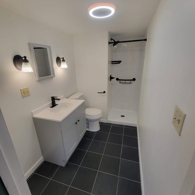Finished Bethlehem bathroom with gray vanity, white shower walls and black fixtures